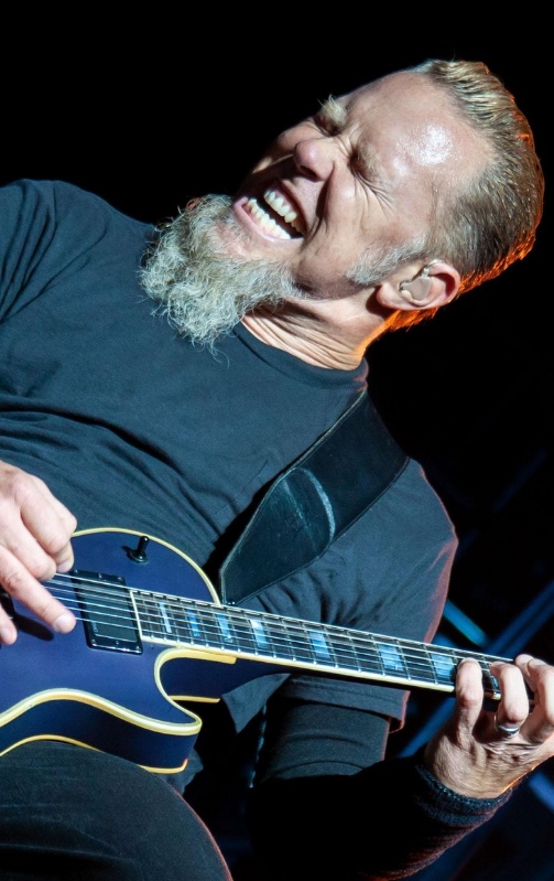 Um homem tocando violão com barba.