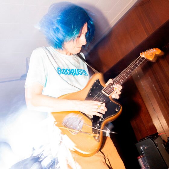 Um homem de cabelo azul tocando violão, dando vida ao melhor do rock em 2023.